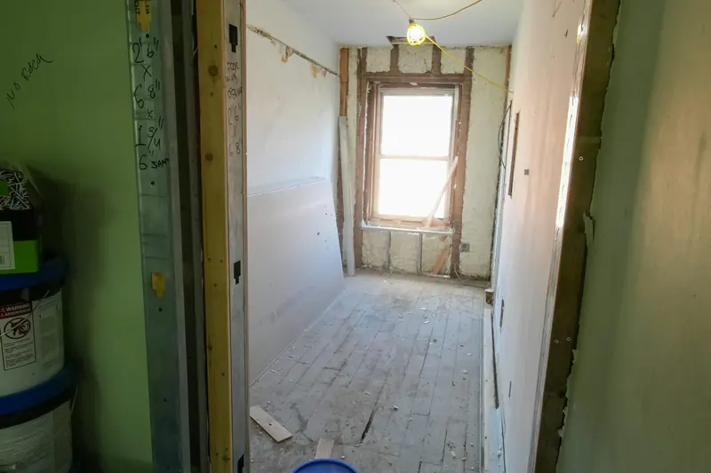 Une pièce en travaux dont le sol, les murs et la porte ne sont pas terminés.
